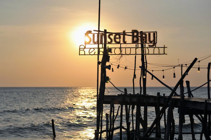 Signature sunset shot with pier sign and ocean horizon